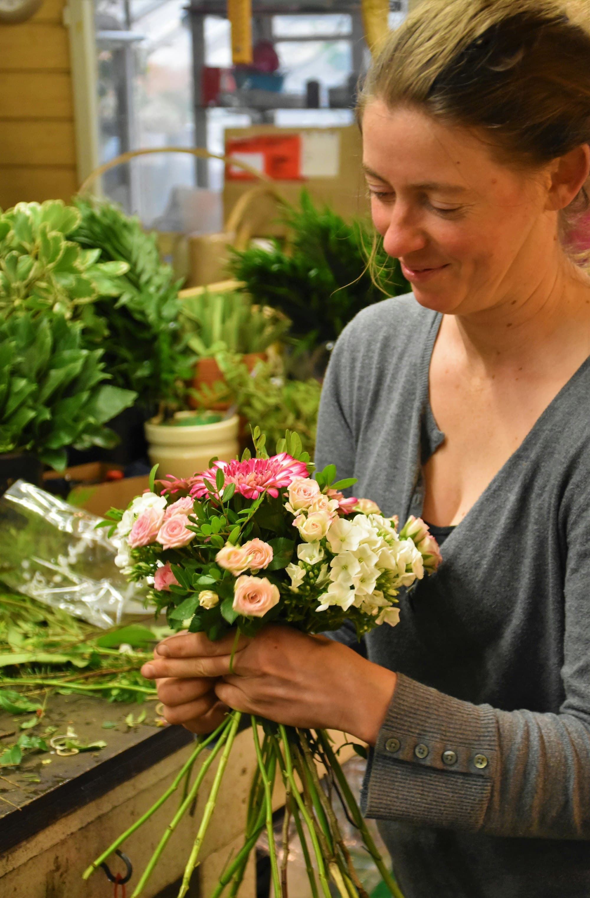 A florist holds a fresh bouquet of pink and white flowers.