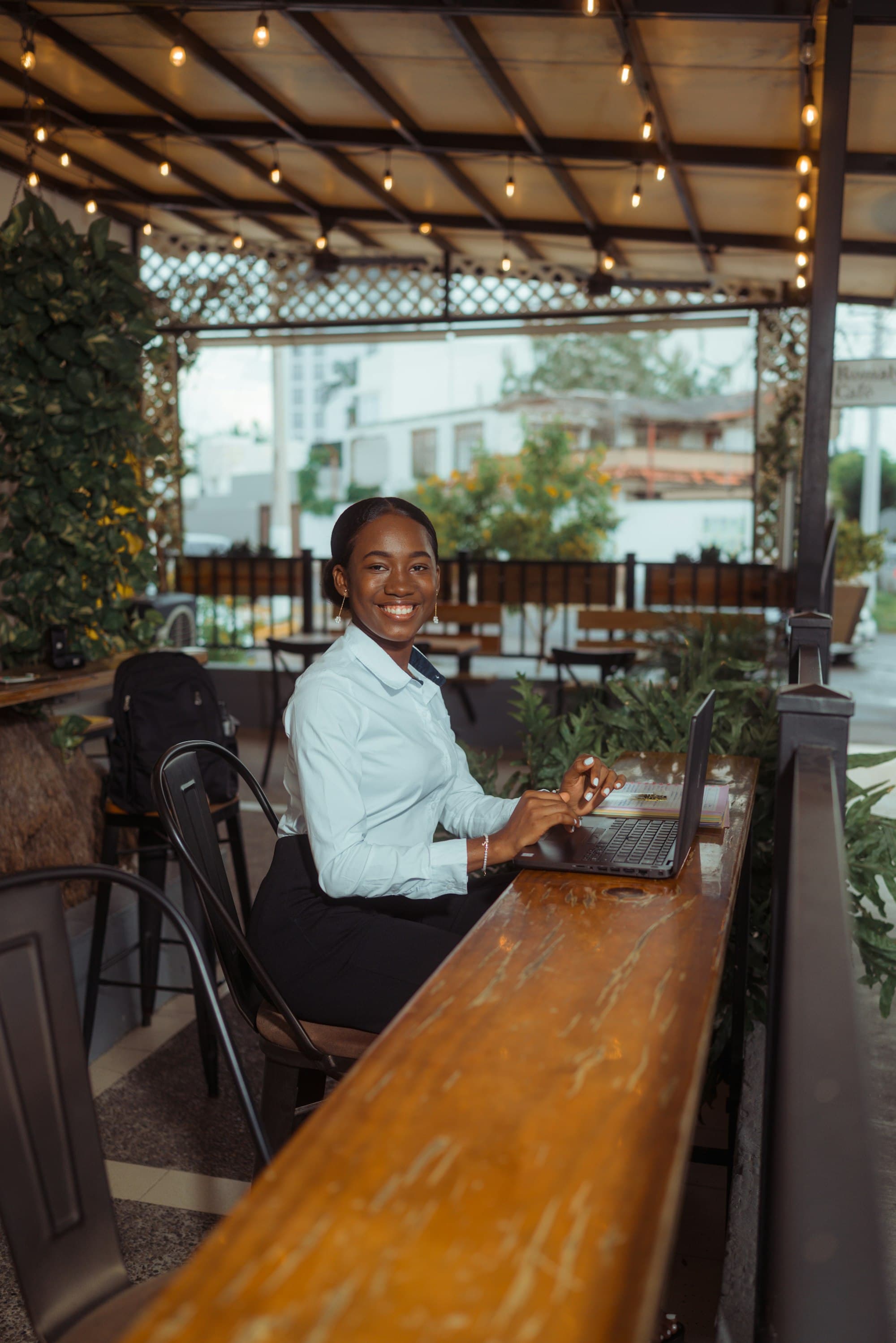 A smiling woman works on her laptop at a café table.