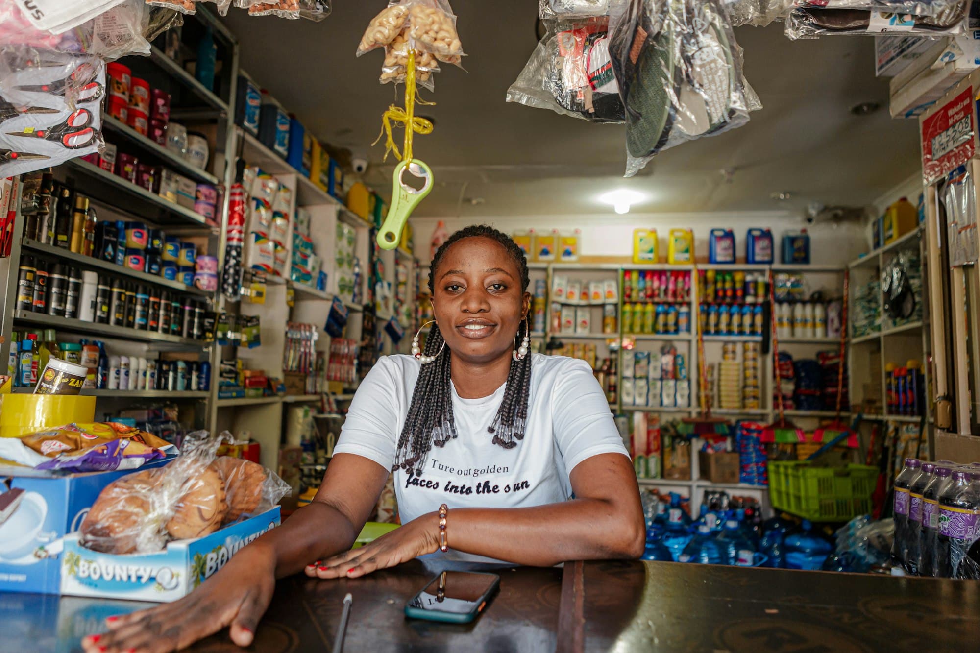 A shopkeeper sits at the counter of her neighborhood store.